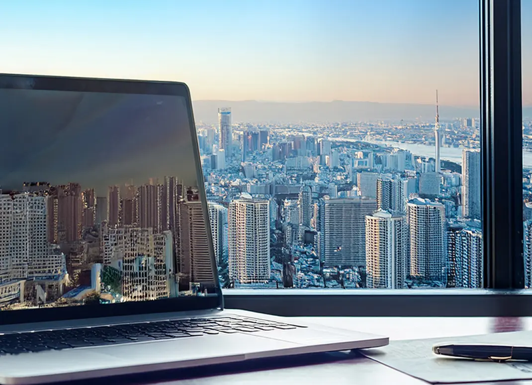 ノートパソコンと都市風景が映るデスクワークのイメージ