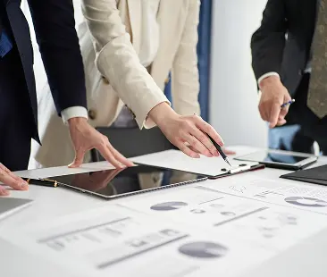 資料とタブレットを使って市場分析を行っている様子