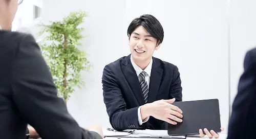 ノートパソコンを前に相談を受けているビジネスパーソン