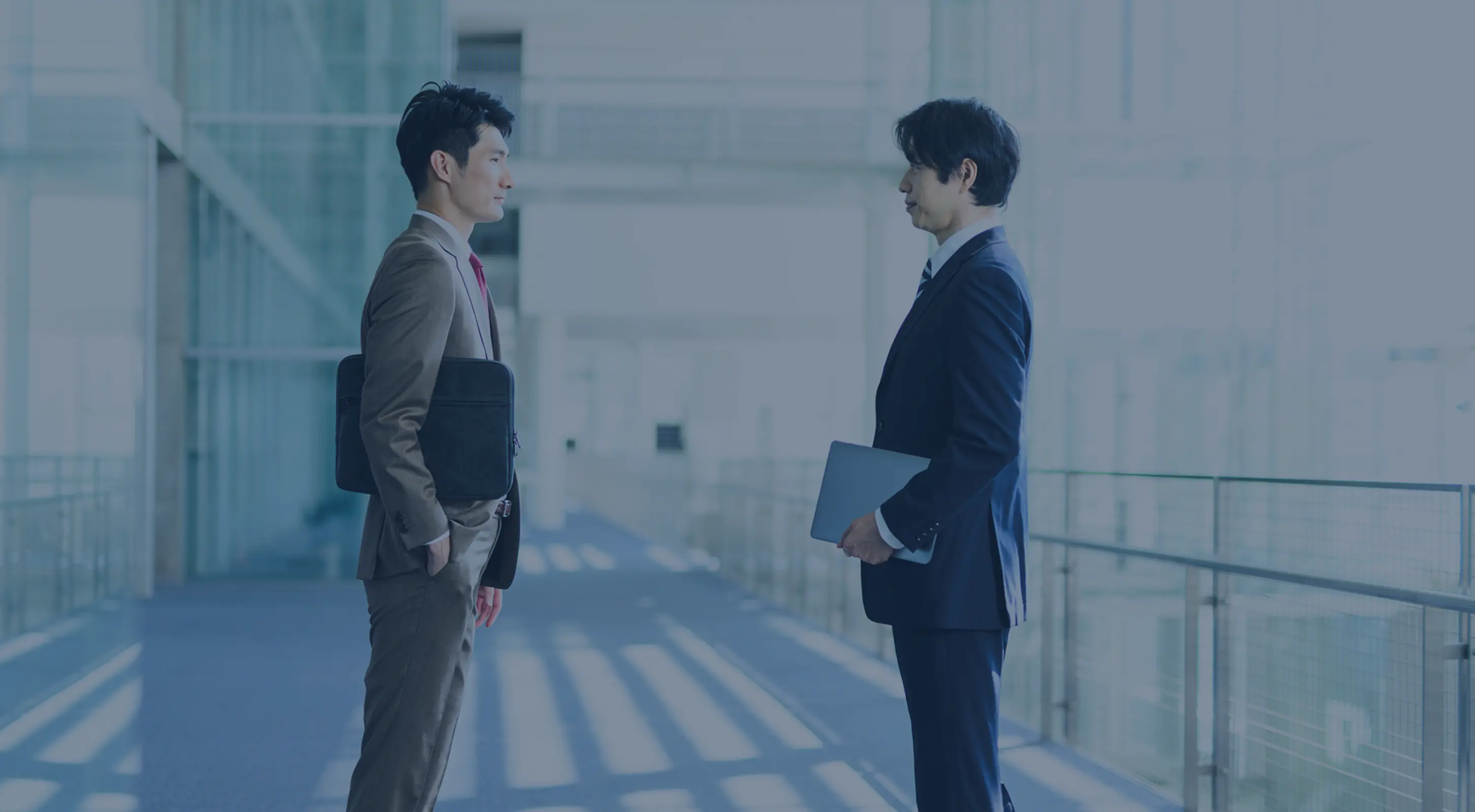 オフィス通路で打ち合わせをするビジネスマン二人